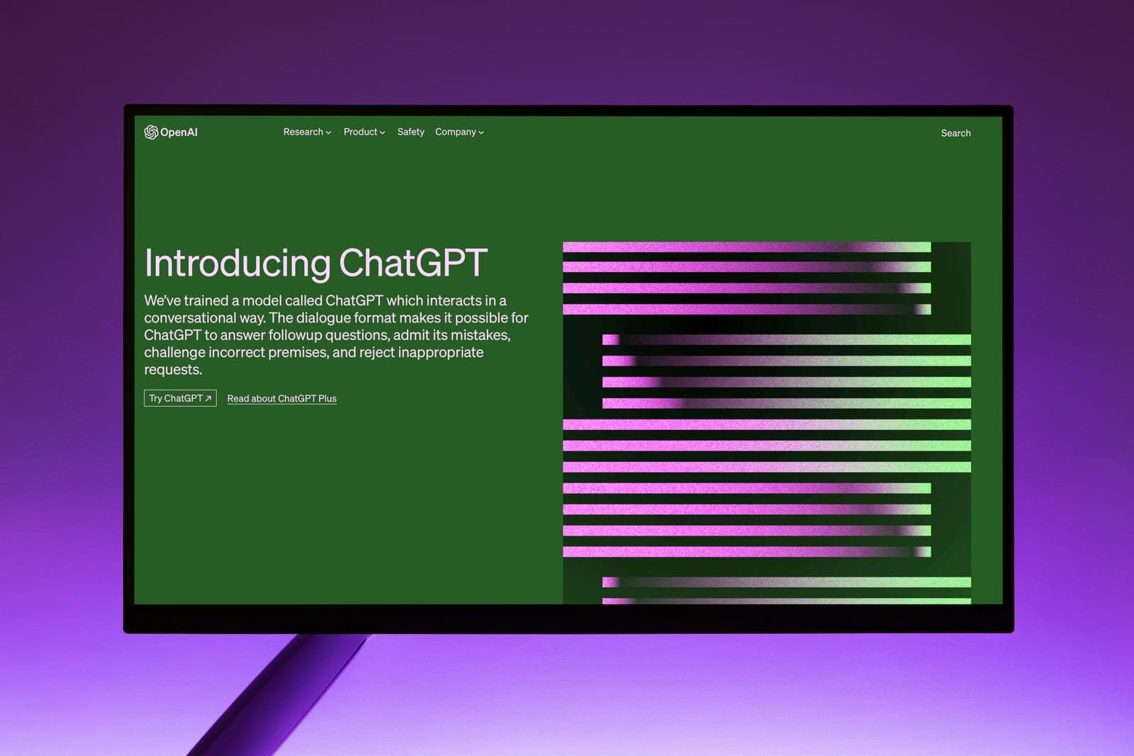 A computer monitor on a purple background showing the OpenAI website announcing ChatGPT.